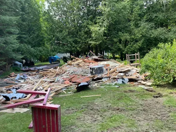 A pile of wood is sitting in the middle of a yard.