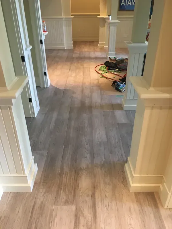 A hallway with a wooden floor and white columns.