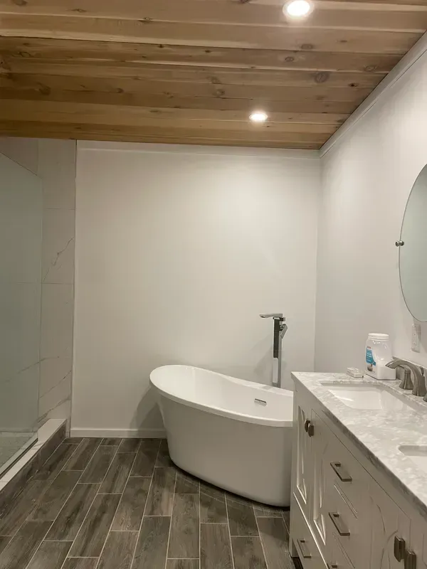A bathroom with a bathtub , sink and mirror.