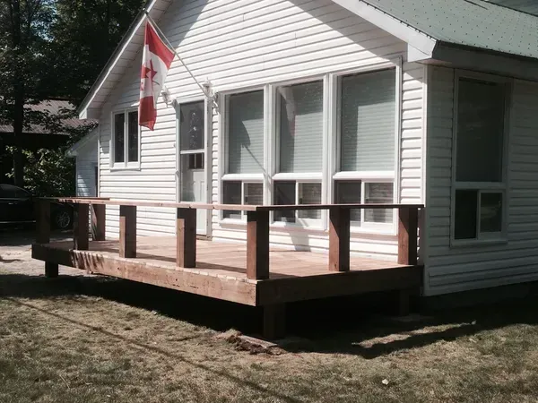 A white house with a wooden deck and a canadian flag