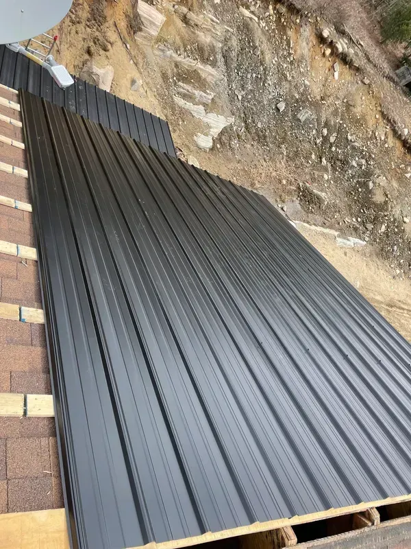 A black metal roof is being installed on top of a brick roof.