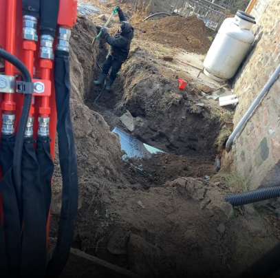 A man is digging a hole in the ground next to a propane tank