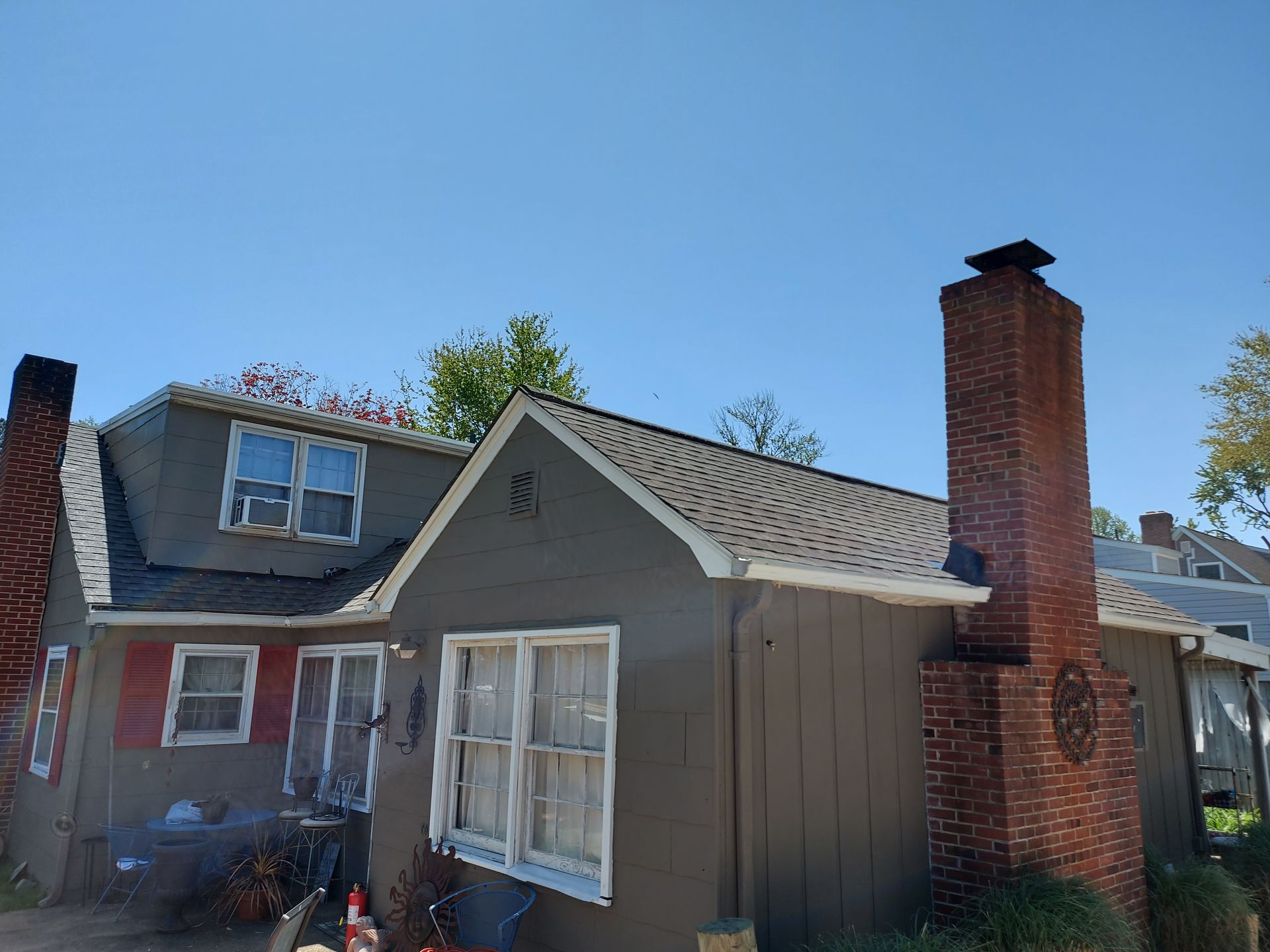 Gray house with two chimneys against a blue sky.