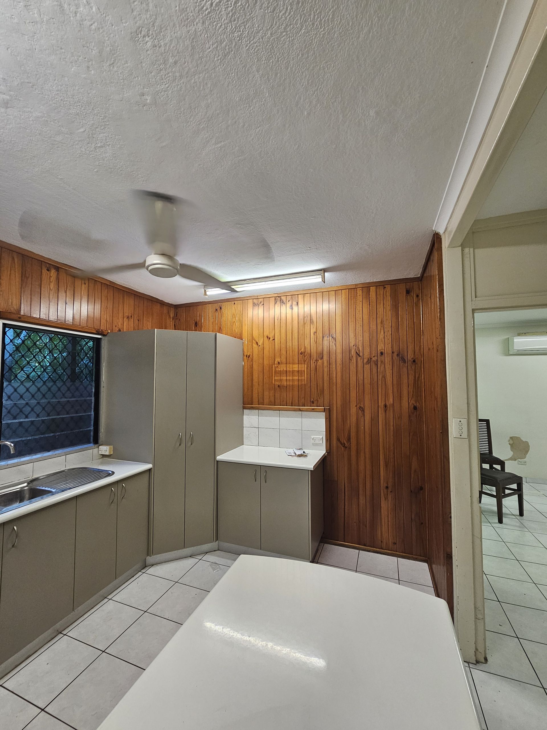 Kitchen with wood-paneled walls, gray cabinets, white appliances, and a white table — Prestige Painting NT in Zuccoli, NT