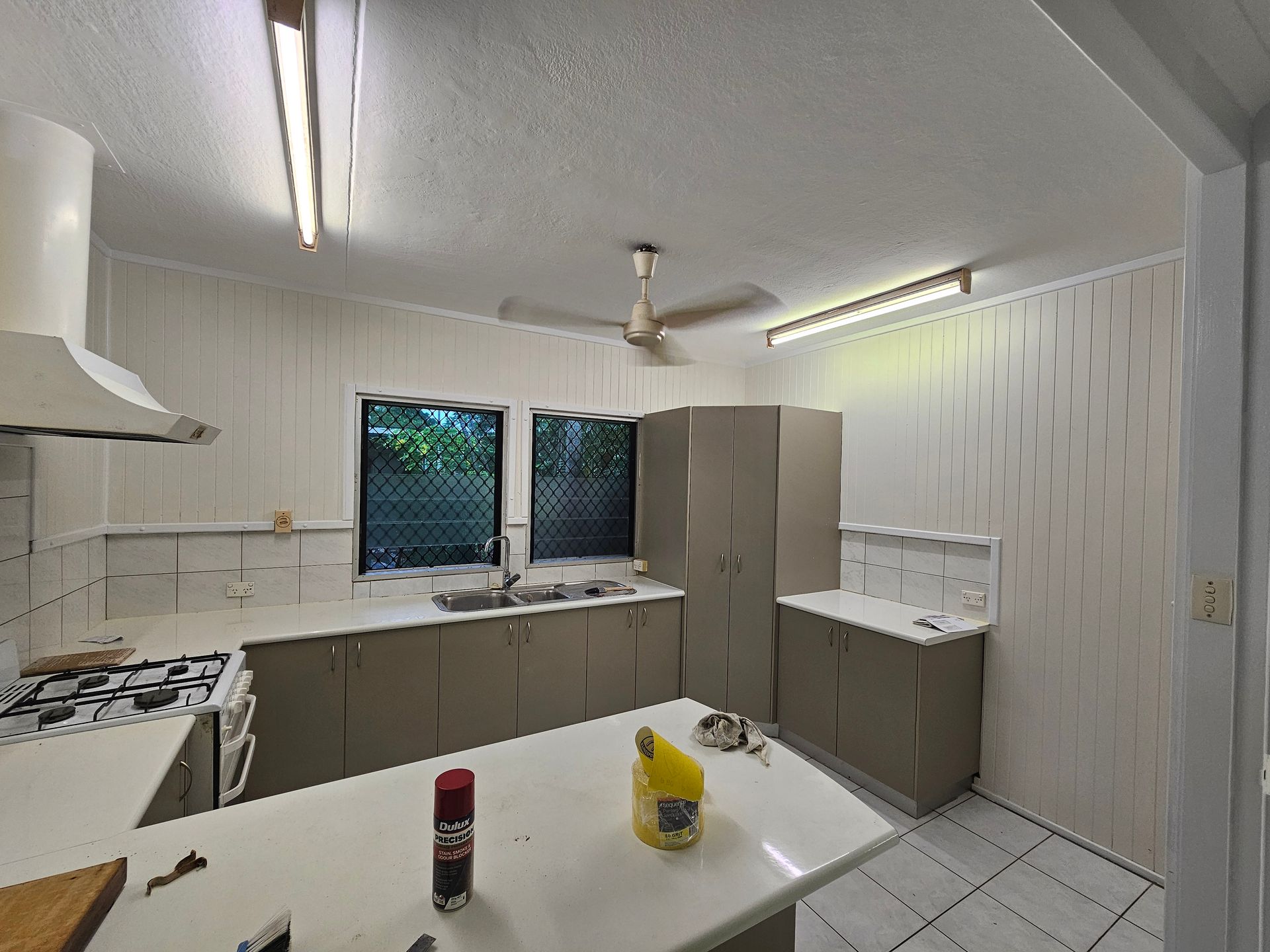 Kitchen interior with light-coloured cabinets, countertops, and appliances. Includes a stove, sink, and island — Prestige Painting NT in Zuccoli, NT