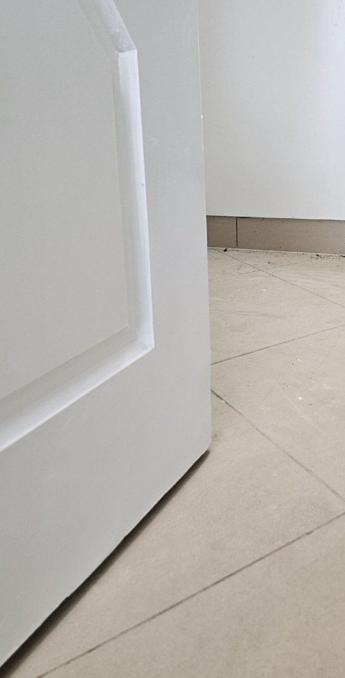 White door slightly ajar on tiled floor. Pale walls and baseboard visible in background — Prestige Painting NT in Zuccoli, NT