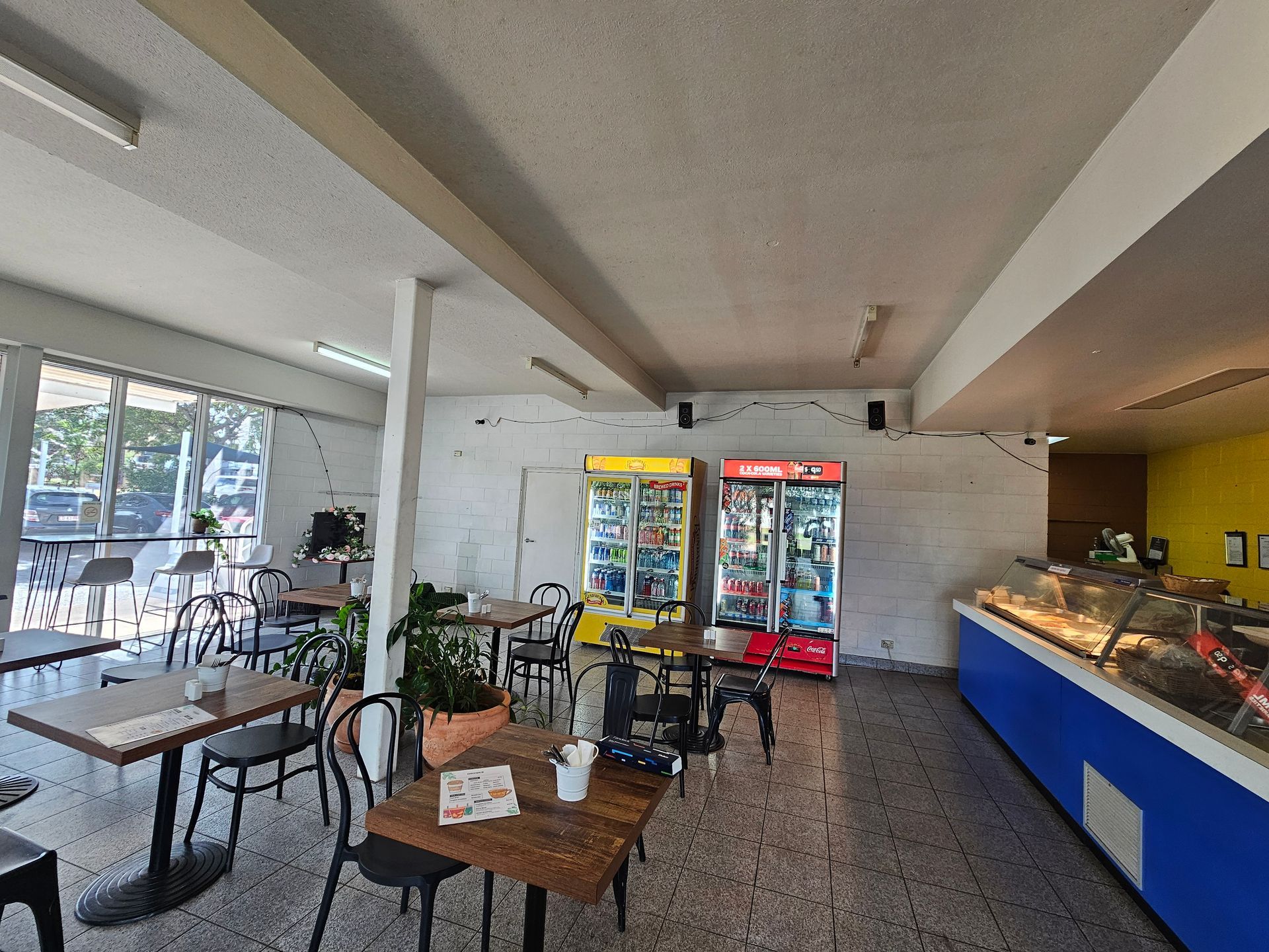 Interior of a cafe with tables, chairs, vending machines, and a display case — Prestige Painting NT in Zuccoli, NT