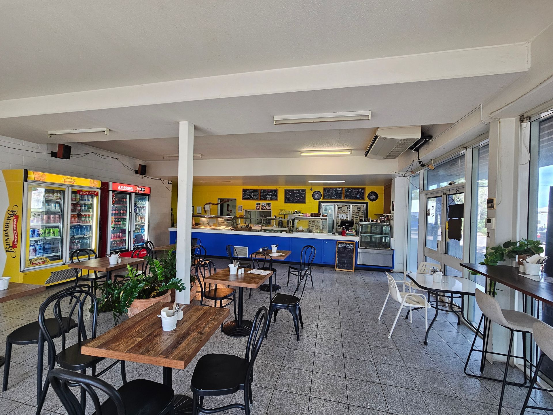 Interior of a cafe with tables, chairs, display counter, fridges, and a window — Prestige Painting NT in Zuccoli, NT