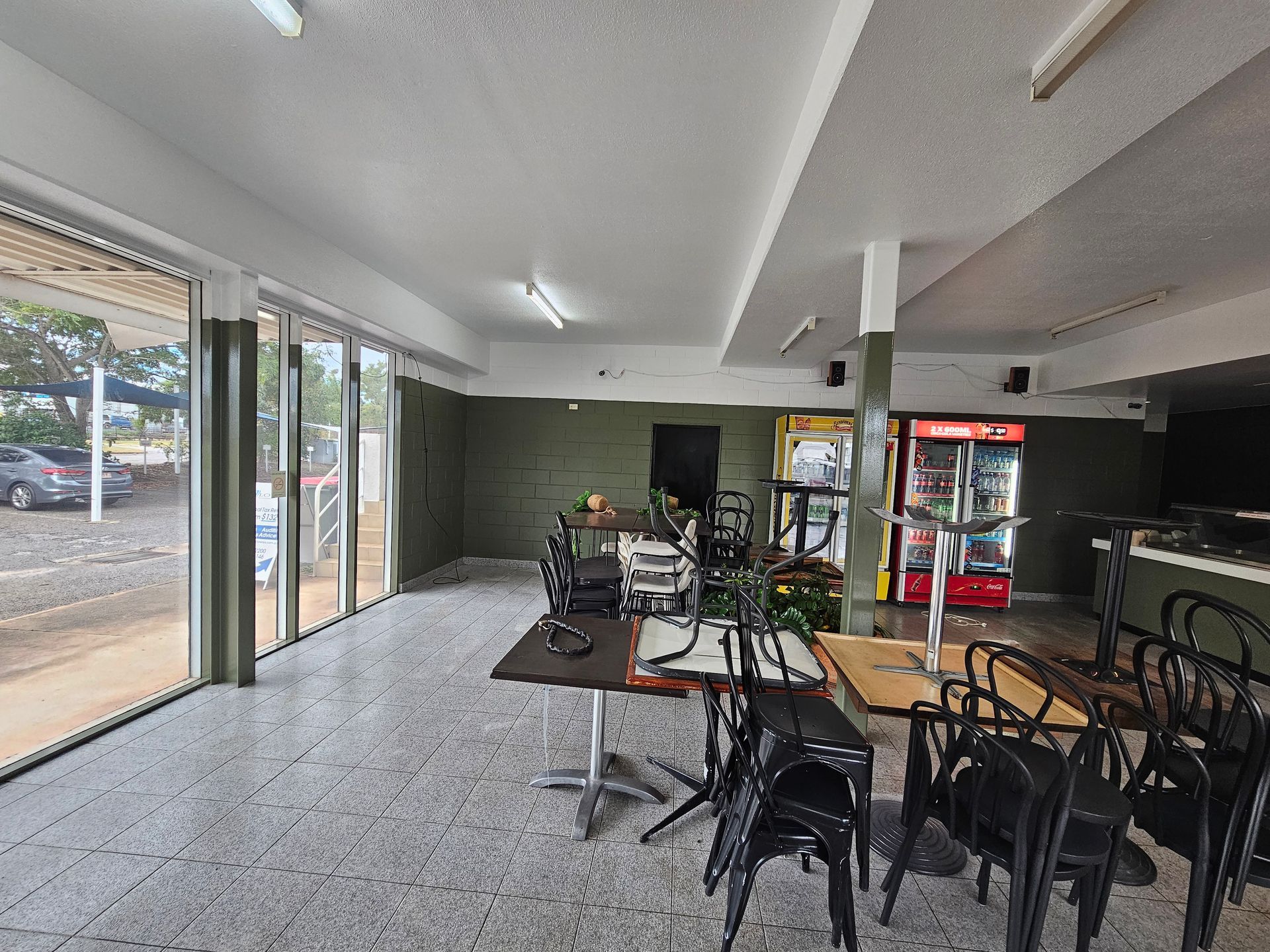 Empty restaurant interior with tables, chairs, arcade games, and a refrigerator against a green-painted wall— Prestige Painting NT in Zuccoli, NT