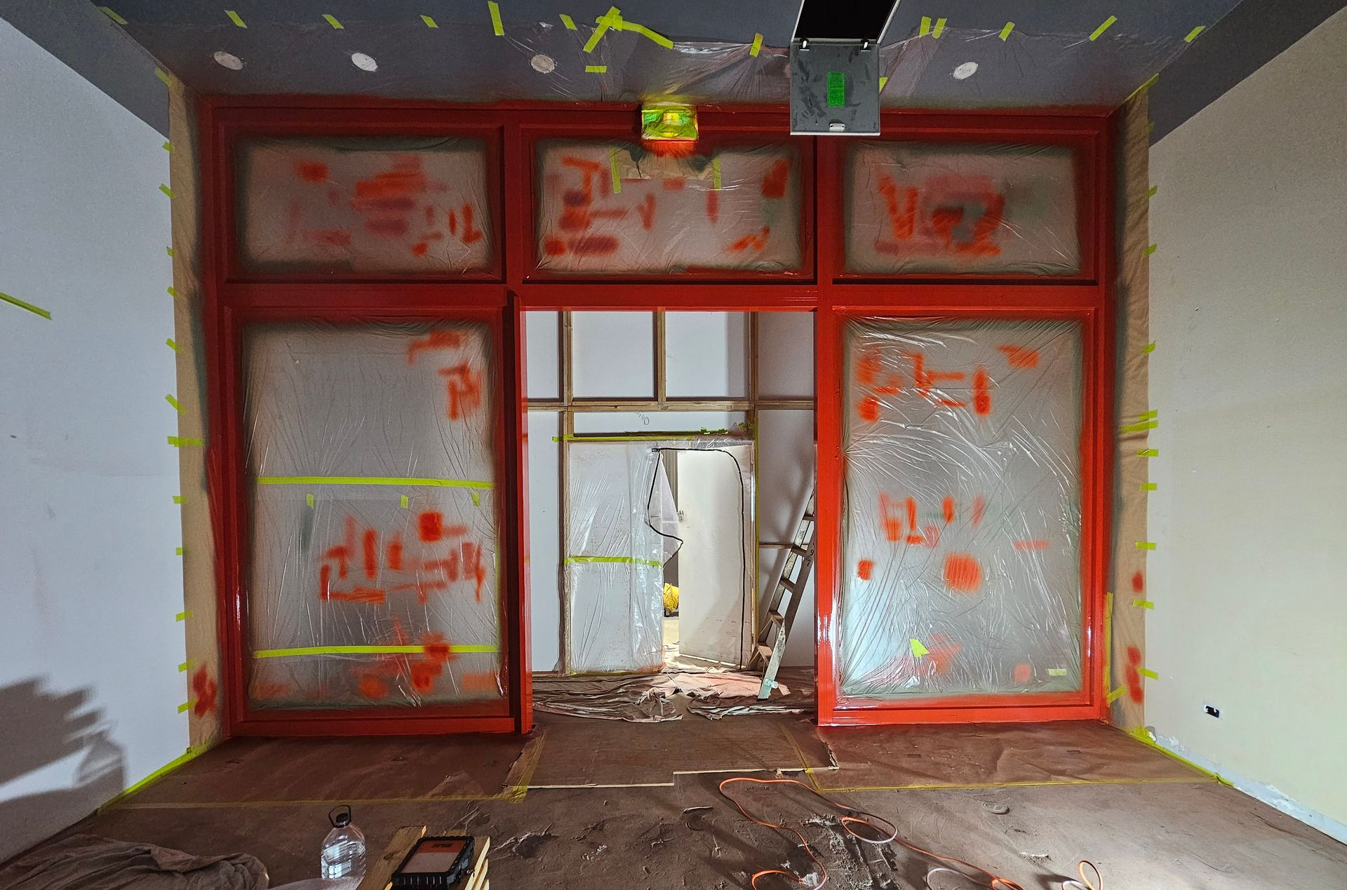 Red-framed doorway with frosted windows, revealing a damaged interior. Debris litters the floor — Prestige Painting NT in Zuccoli, NT