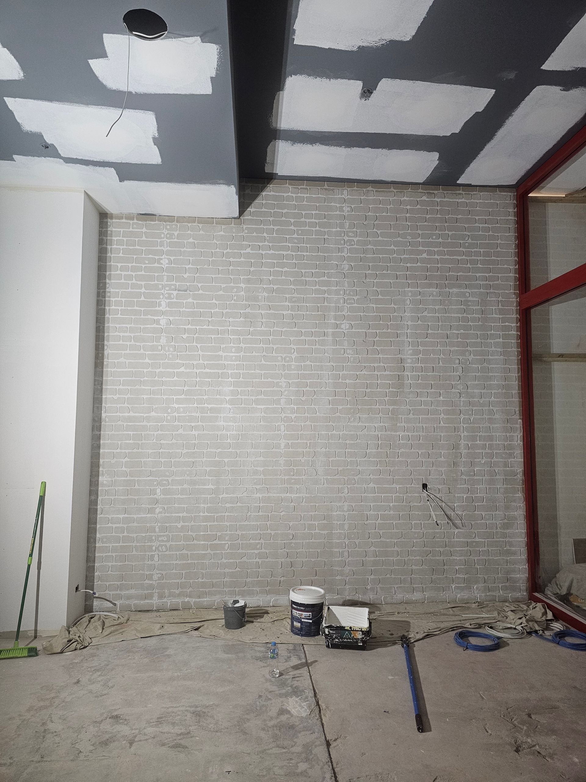 Interior construction site with gray brick wall, drywall ceiling, and tools on floor — Prestige Painting NT in Zuccoli, NT