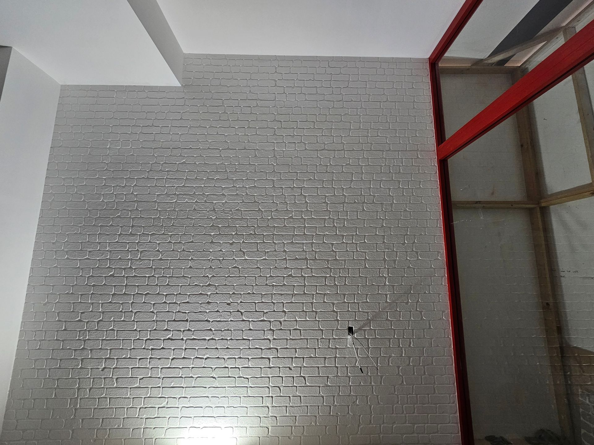 Brick wall with metallic finish, next to red door frame. White ceiling on top — Prestige Painting NT in Zuccoli, NT