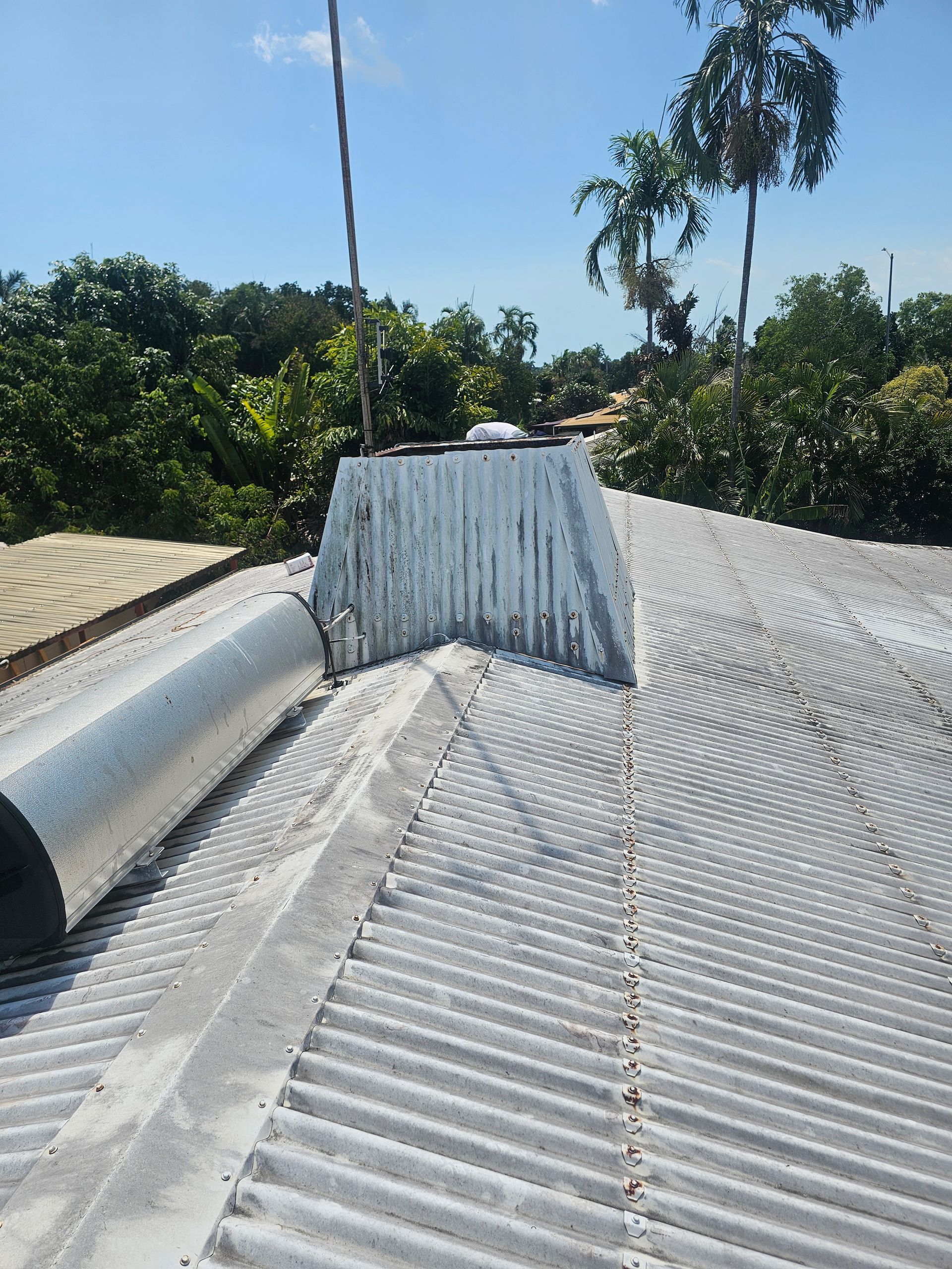 Corrugated metal roof with silver roll of material; trees and blue sky background — Prestige Painting NT in Zuccoli, NT