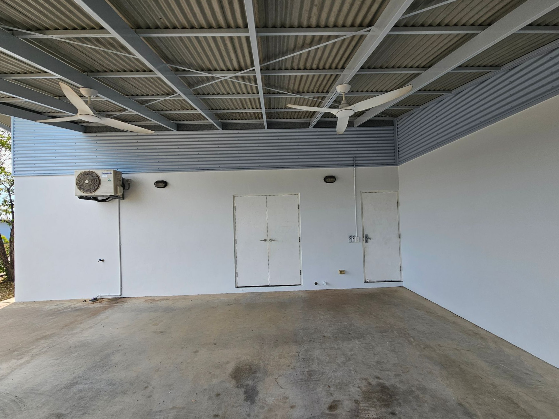 Covered outdoor area with white walls, doors, and fans. Concrete floor. Metal roof — Prestige Painting NT in Zuccoli, NT