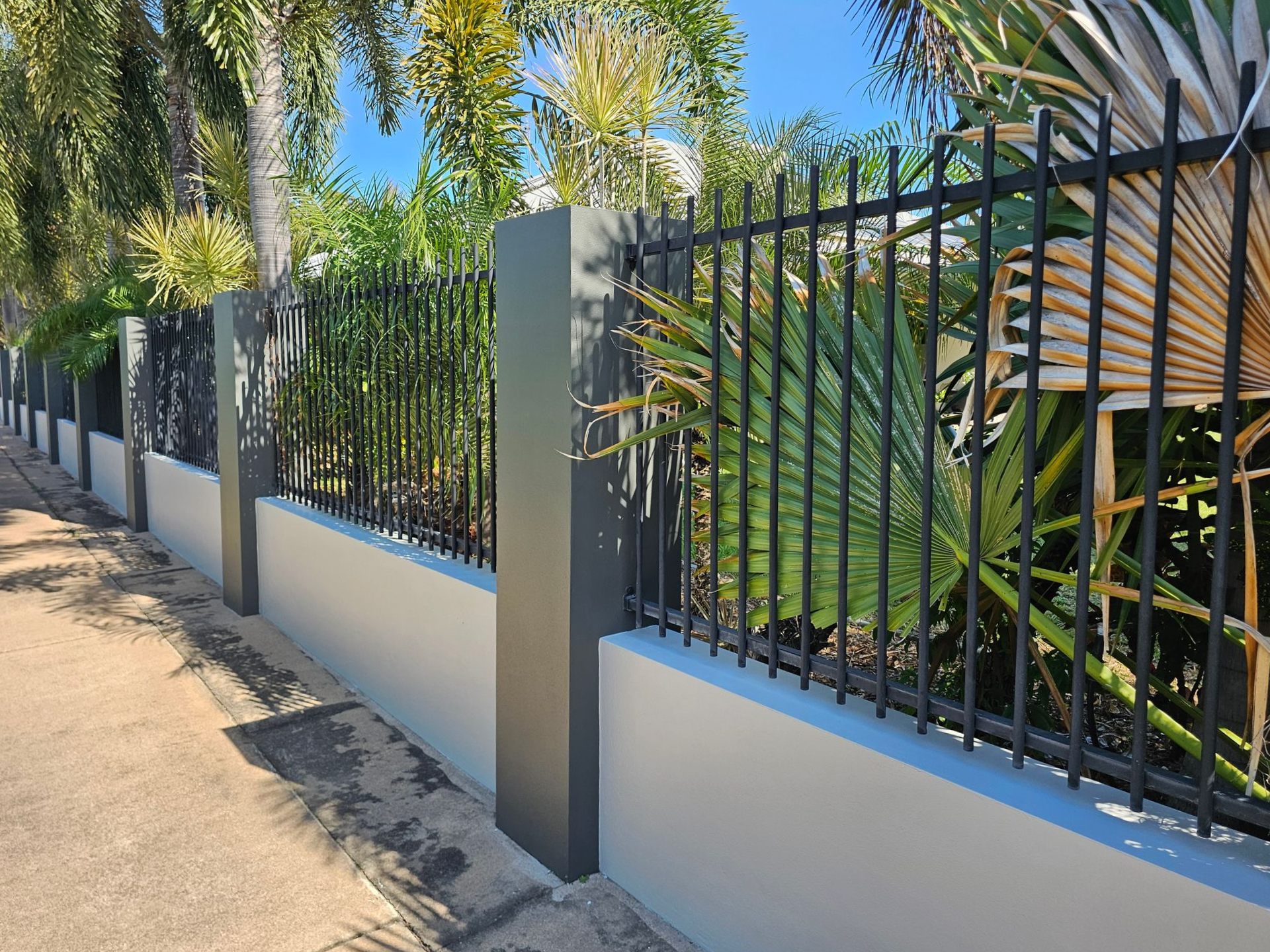 Black Metal Fence With Grey Pillars on a White Wall, Along a Sidewalk With Palm Trees — Prestige Painting NT in Zuccoli, NT