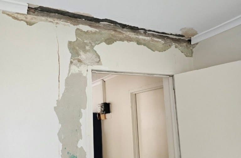 Damaged wall corner showing exposed plaster and dark material above a doorway. White walls, ceiling, and trim — Prestige Painting NT in Zuccoli, NT