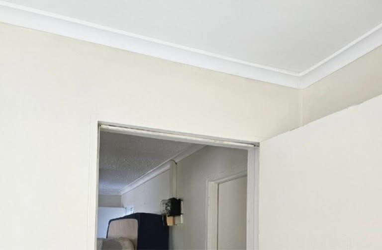 Corner of a room with white crown molding. Beige walls, open doorway into a hallway — Prestige Painting NT in Zuccoli, NT