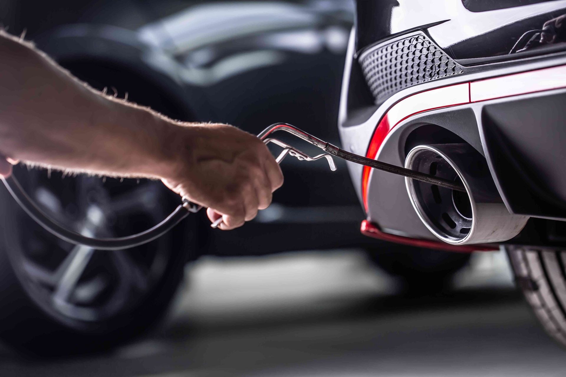a person is using a wrench to fix a car exhaust pipe