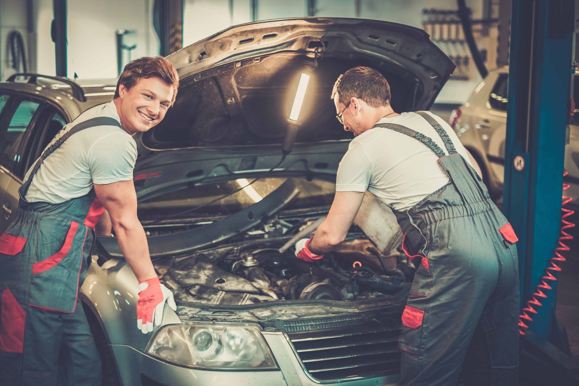 two men are working on a car with the hood open