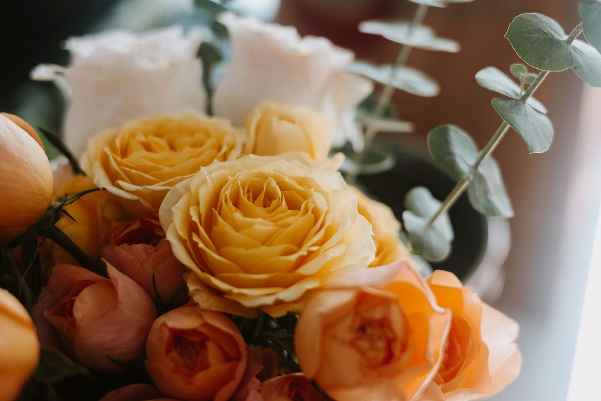 Bouquet of yellow and peach roses with white flowers and greenery in soft natural light