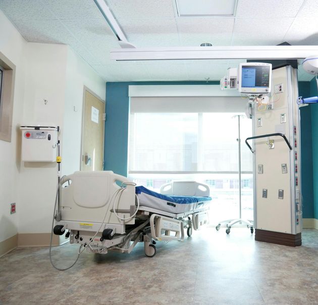 Empty hospital room with a bed, monitor, and bright window light