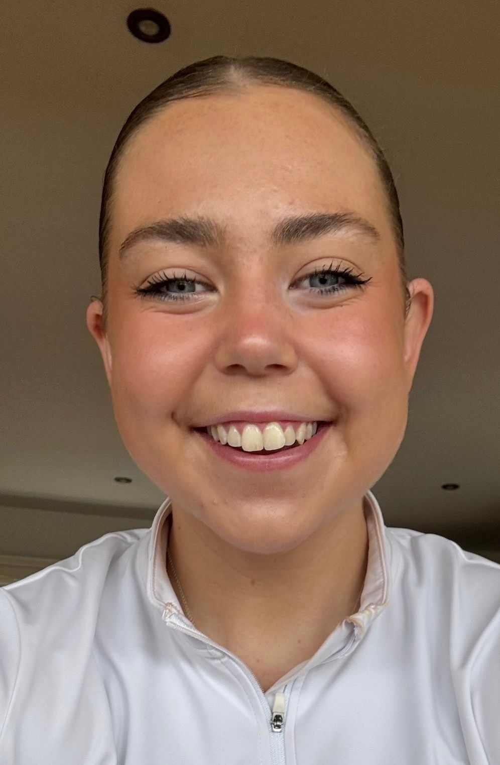 Smiling person in a white shirt against a warm indoor background