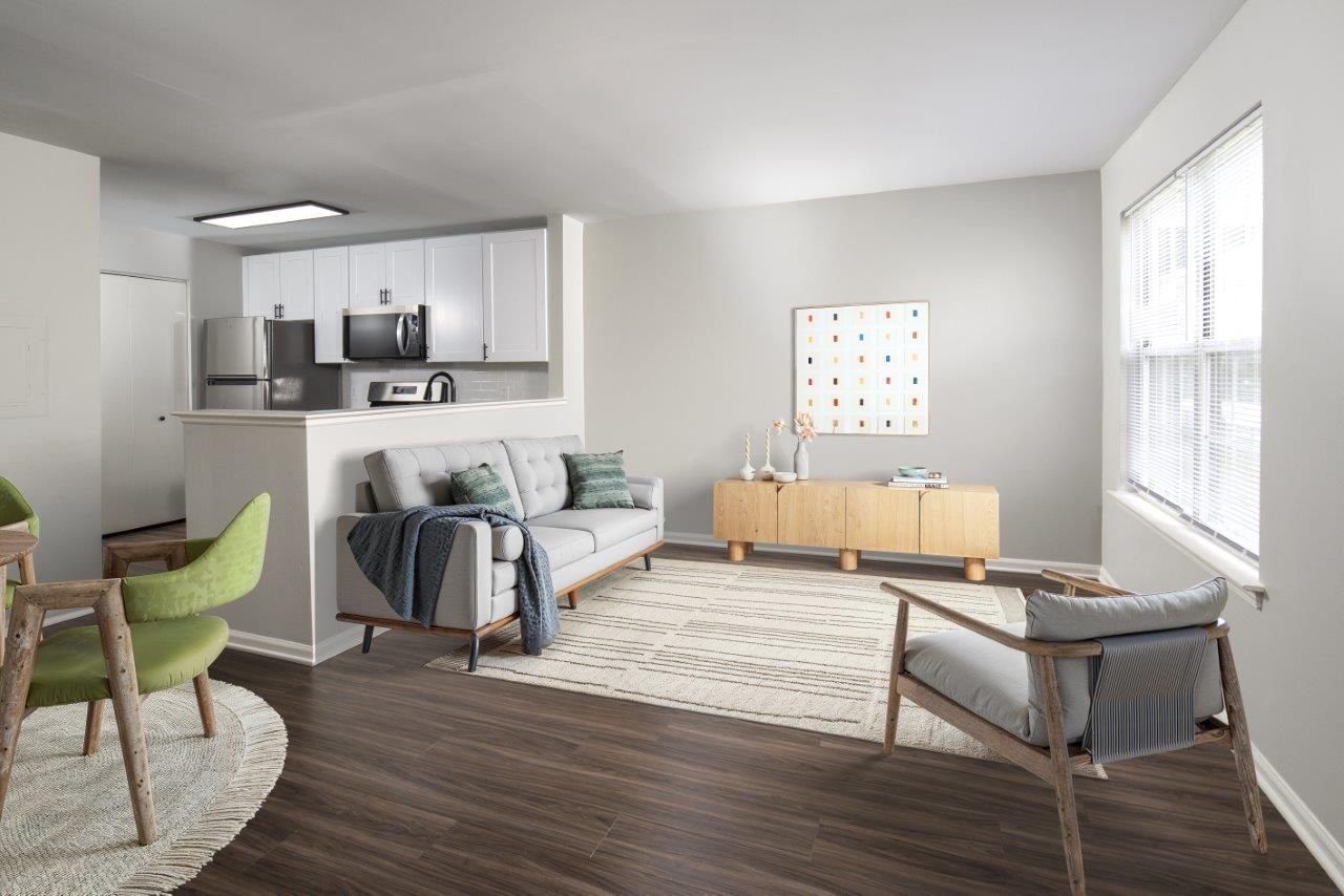 Modern living room with gray sofa, green chair, wood console, and large window with blinds
