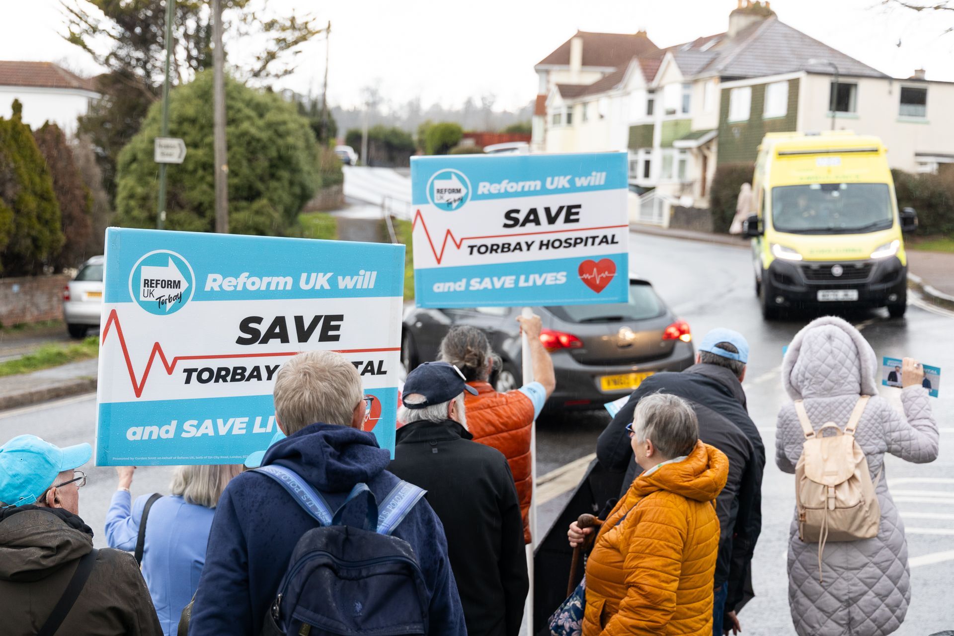 A group of people are walking down a street holding signs.