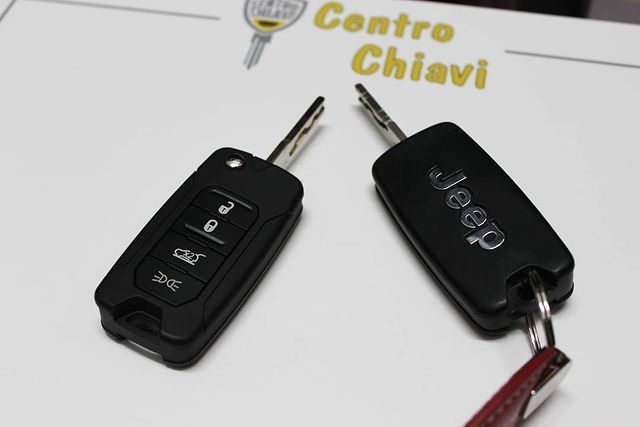 Due telecomandi neri per auto Jeep su una superficie bianca con il logo del Centro Chiavi sullo sfondo.