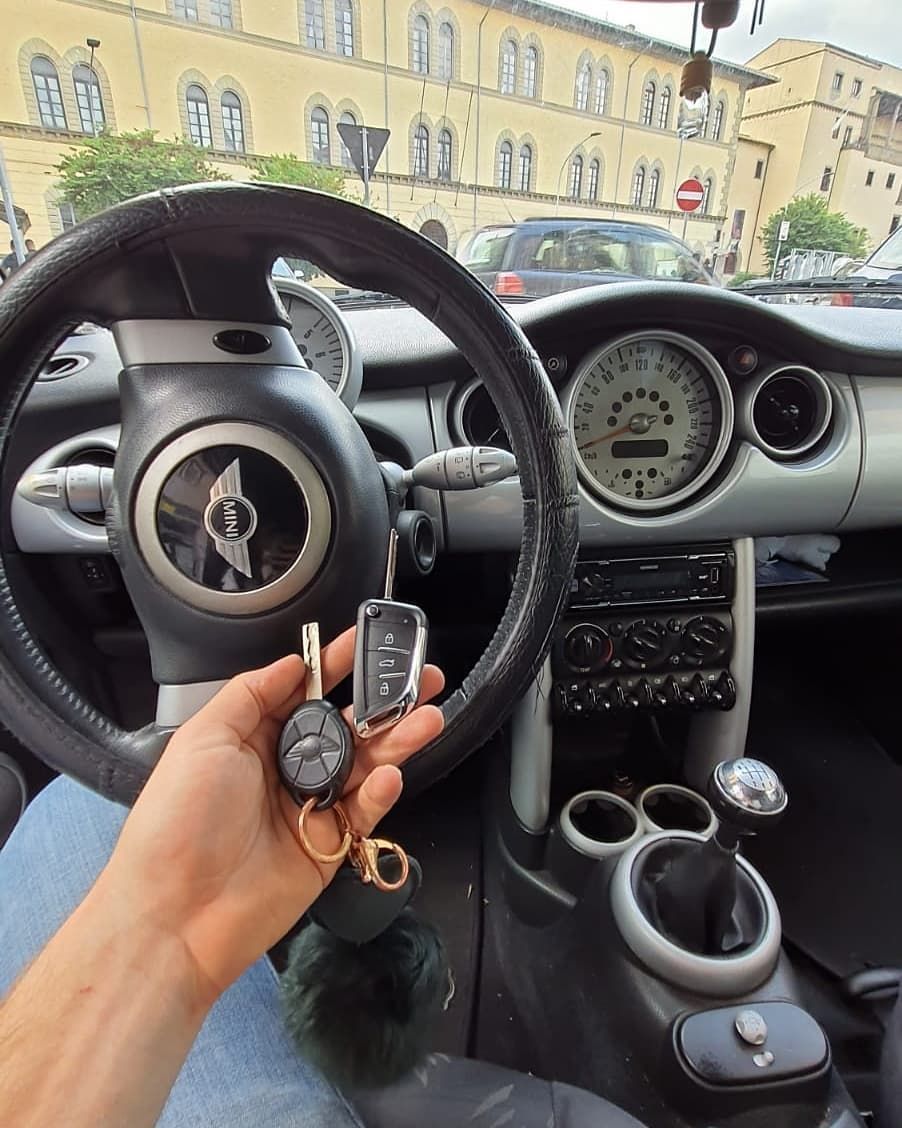 Vista dal punto di vista del guidatore degli interni di una Mini Cooper con le chiavi in ​​mano e una strada cittadina fuori dal parabrezza.