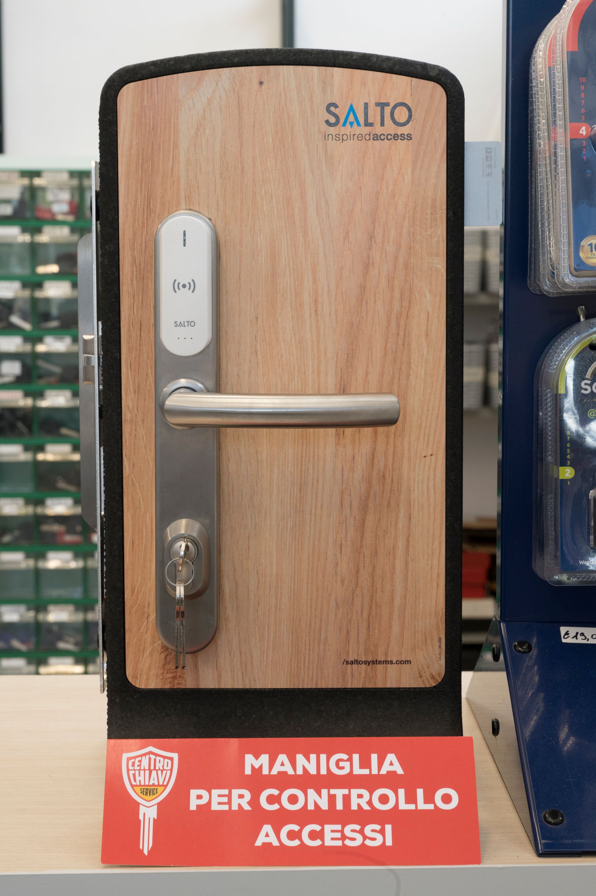 Maniglia per porta SALTO in legno con pannello di controllo accessi e cartello rosso con la scritta “MANIGLIA PER CONTROLLO ACCESSI”