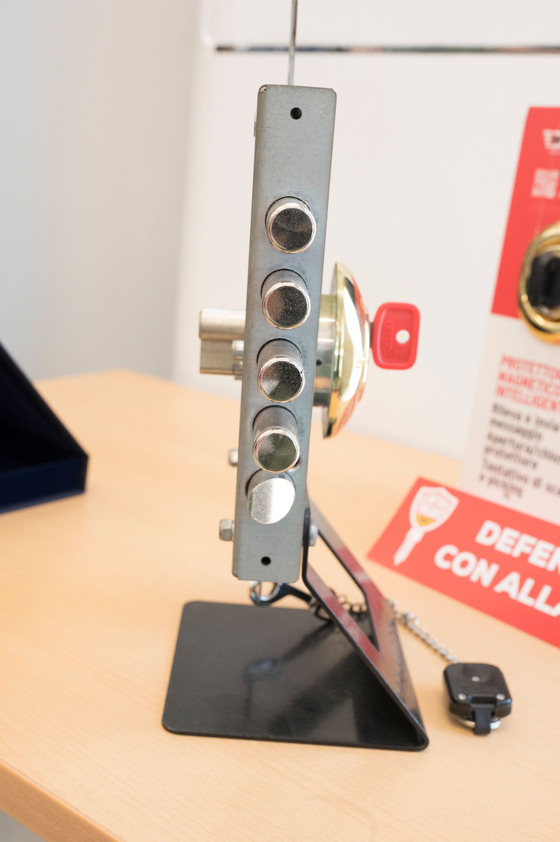 Dispositivo metallico su un supporto nero con quattro pulsanti circolari, esposto su un tavolo in un negozio.