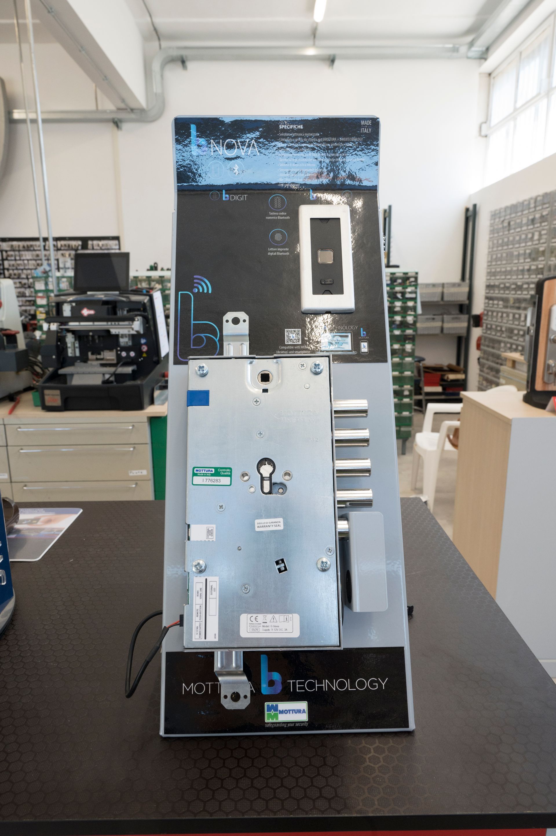 Macchina o apparecchio metallico su un banco da lavoro in un laboratorio o in un'officina, vista frontale con pannello di controllo e display.