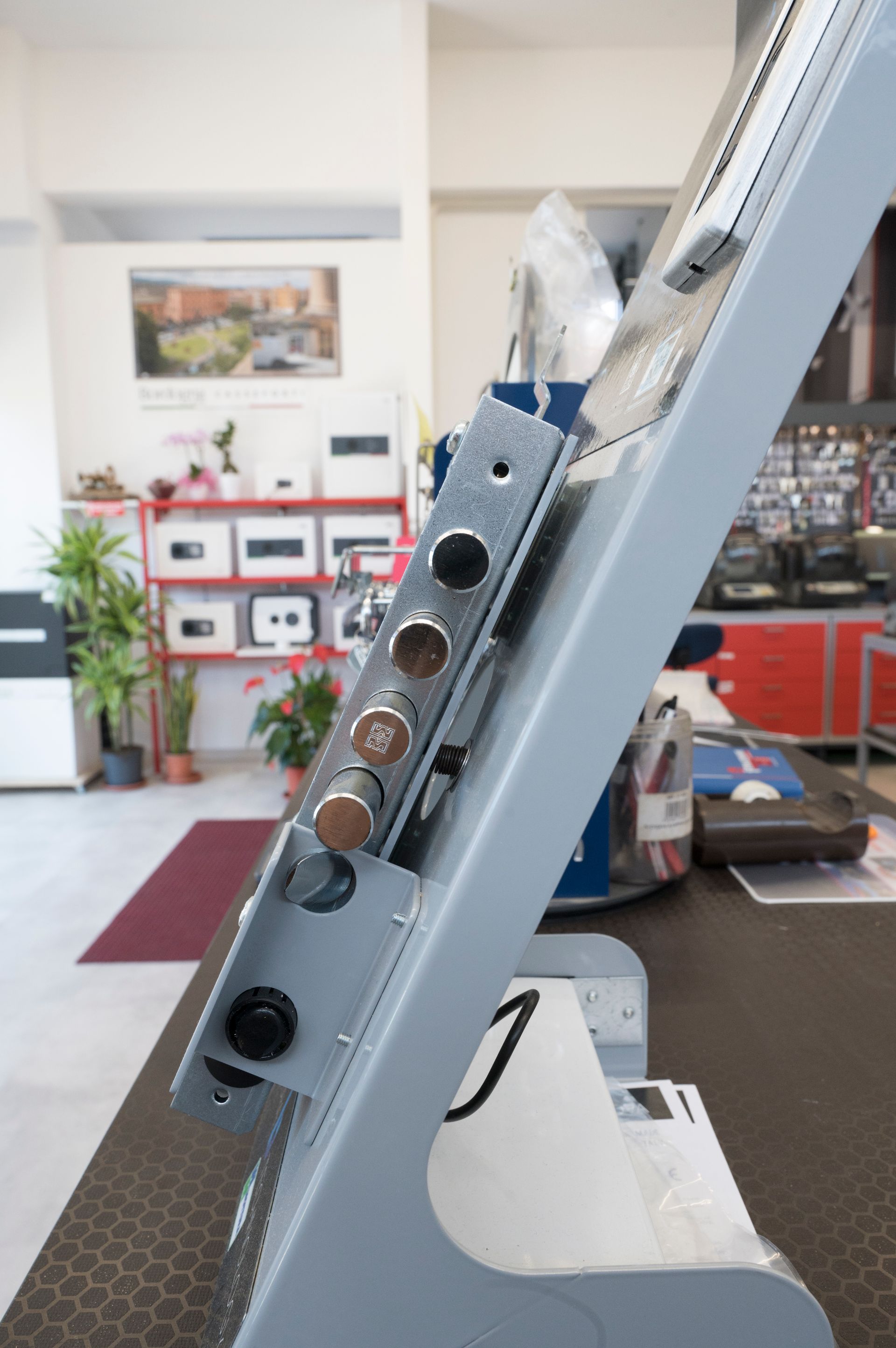 Primo piano di una struttura metallica grigia ad angolo con pulsanti, all'interno di un'officina o di un garage.