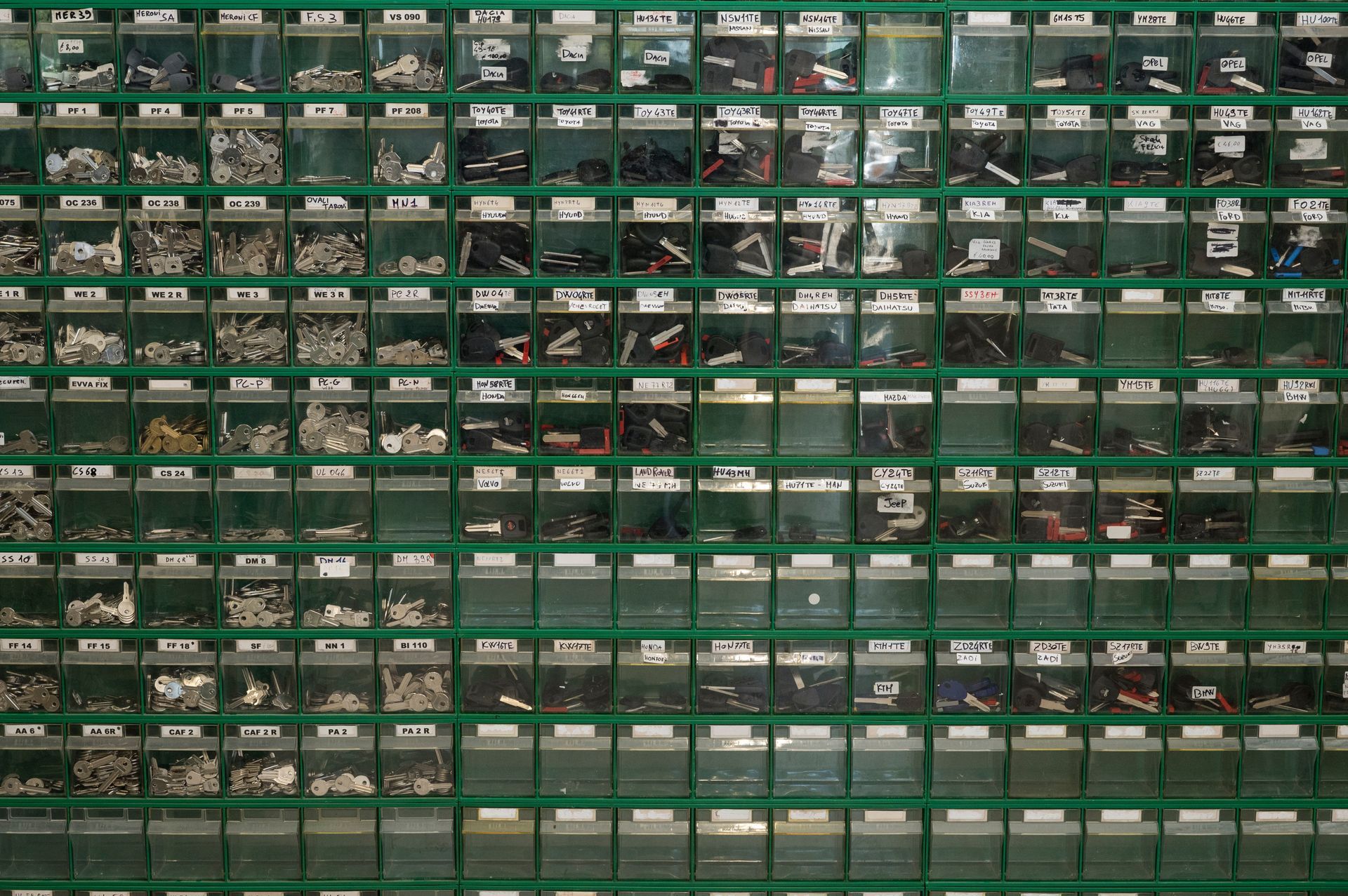 File di contenitori verdi pieni di piccoli componenti in una scaffalatura industriale.
