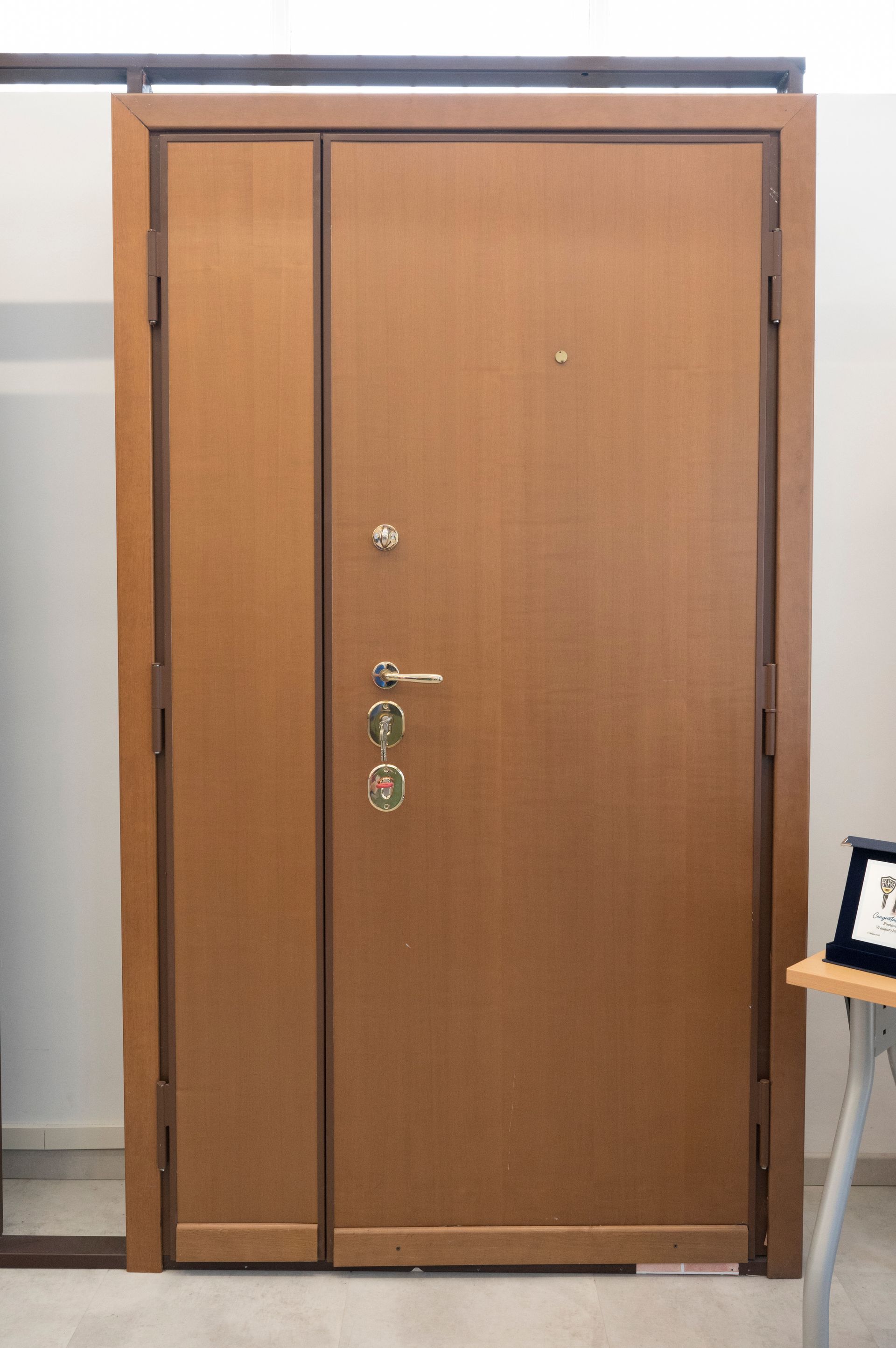 Doppia porta in legno con maniglie in metallo e spioncino in un corridoio interno.