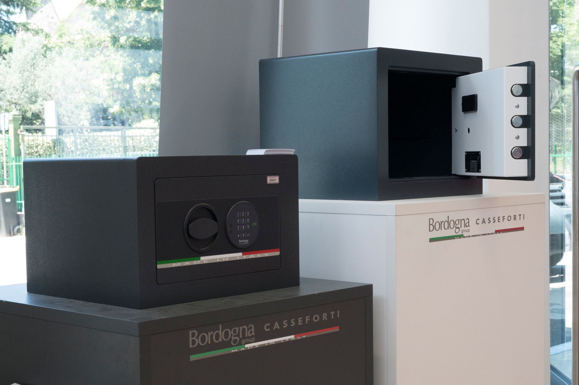 Esposizione di apparecchiature audio nere su piedistalli in uno showroom luminoso, con uno sportello aperto.