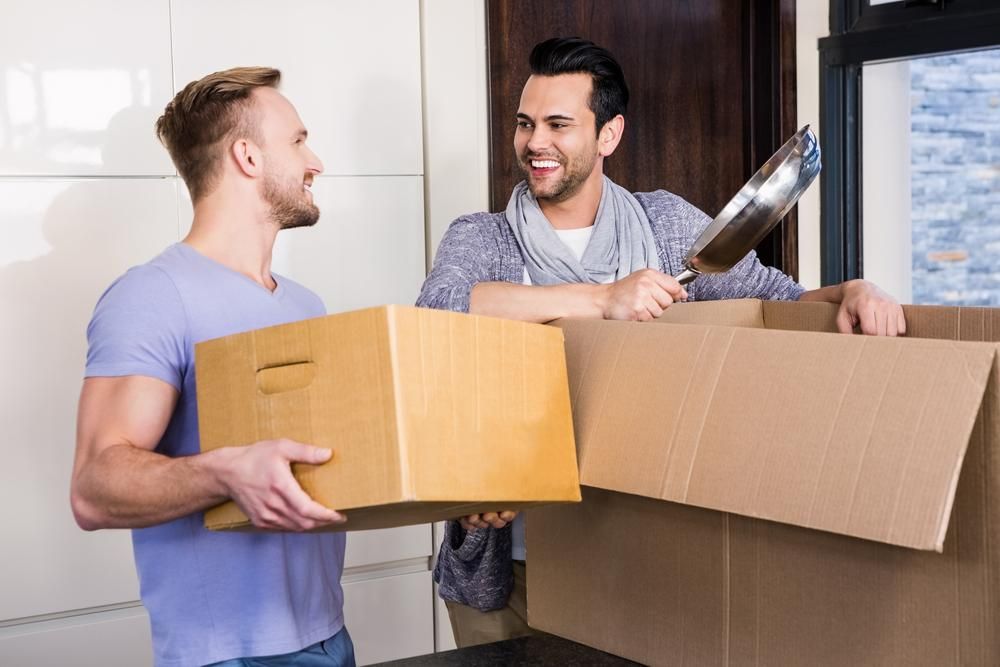 Two Men Are Carrying Cardboard Boxes Into A New Home — Brisbane Moving & Storage In Acacia Ridge, QLD