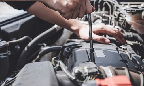 Mechanic tightening a car engine bolt in an open hood bay