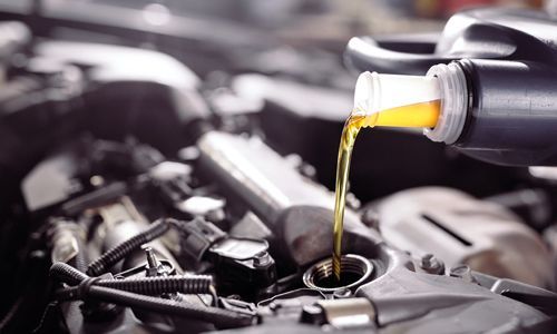 Motor oil pouring from a bottle into a car engine