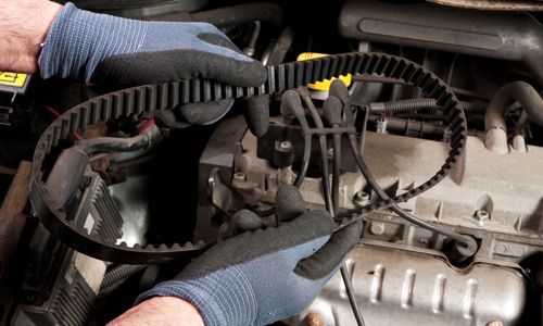 Gloved hands working on car engine wiring under the hood