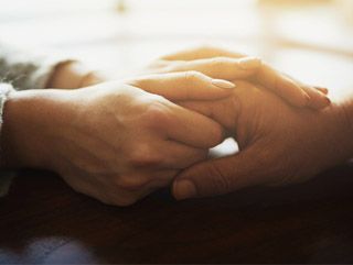 Two people holding hands in a sign of comfort and support