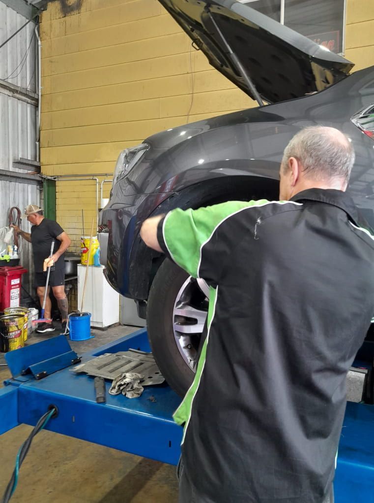 A Man is Changing a Tire on a Car in a Garage — CB Automotive In Yatala, QLD
