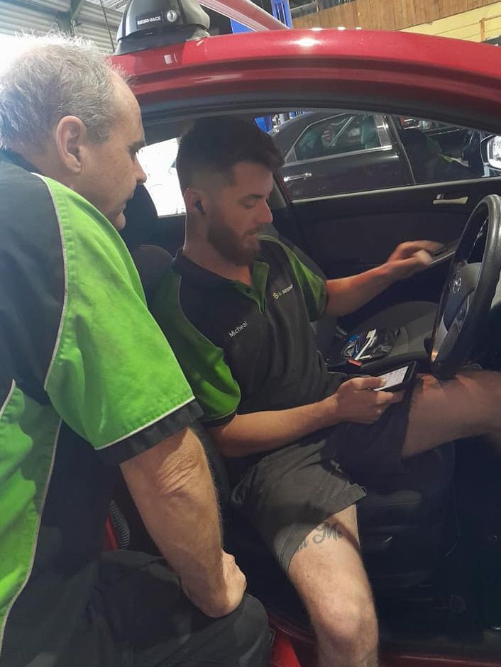 Two Men Are Sitting in a Car Looking at a Tablet — CB Automotive In Yatala, QLD