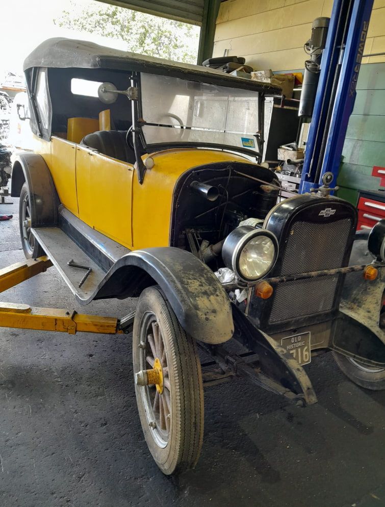 An Old Yellow Car is Sitting on a Lift in a Garage — CB Automotive In Yatala, QLD