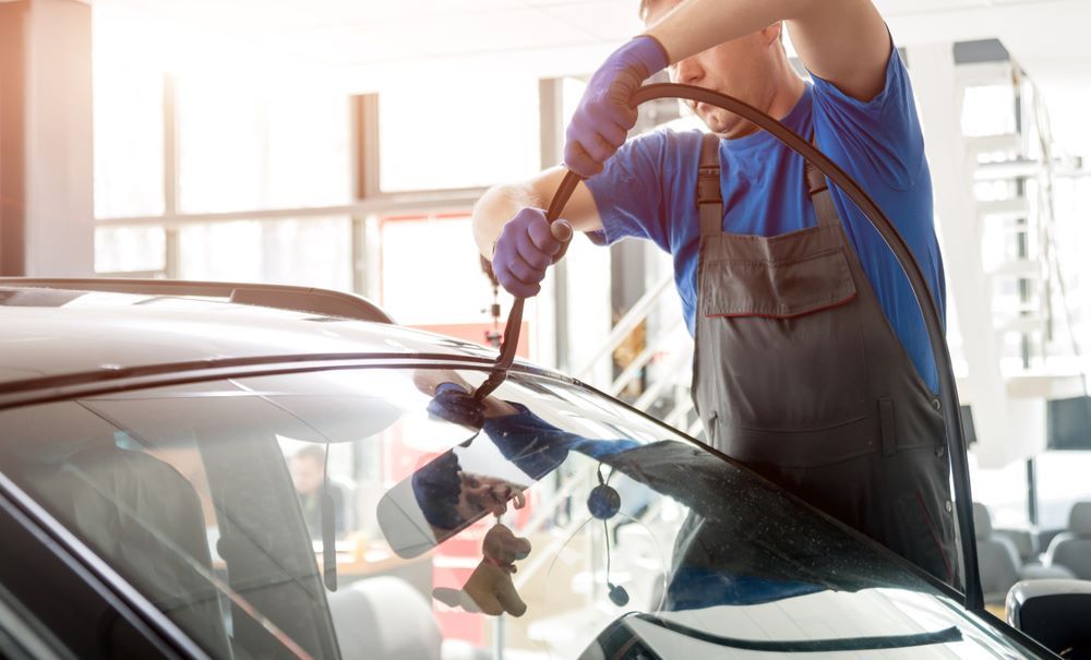 Two Men Are Working on a Windshield in a Garage — Keppel Coast Windscreens in Yeppoon, QLD