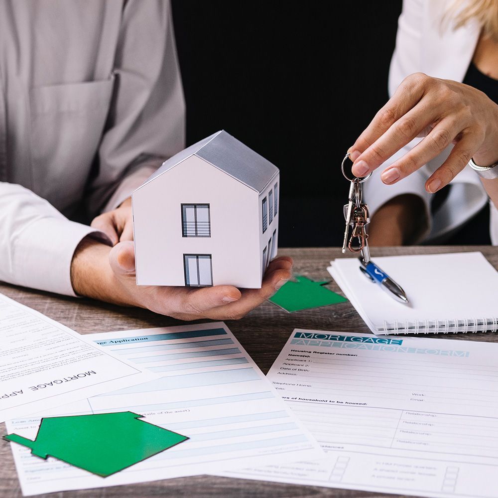 A person is holding a model house and keys in their hands.