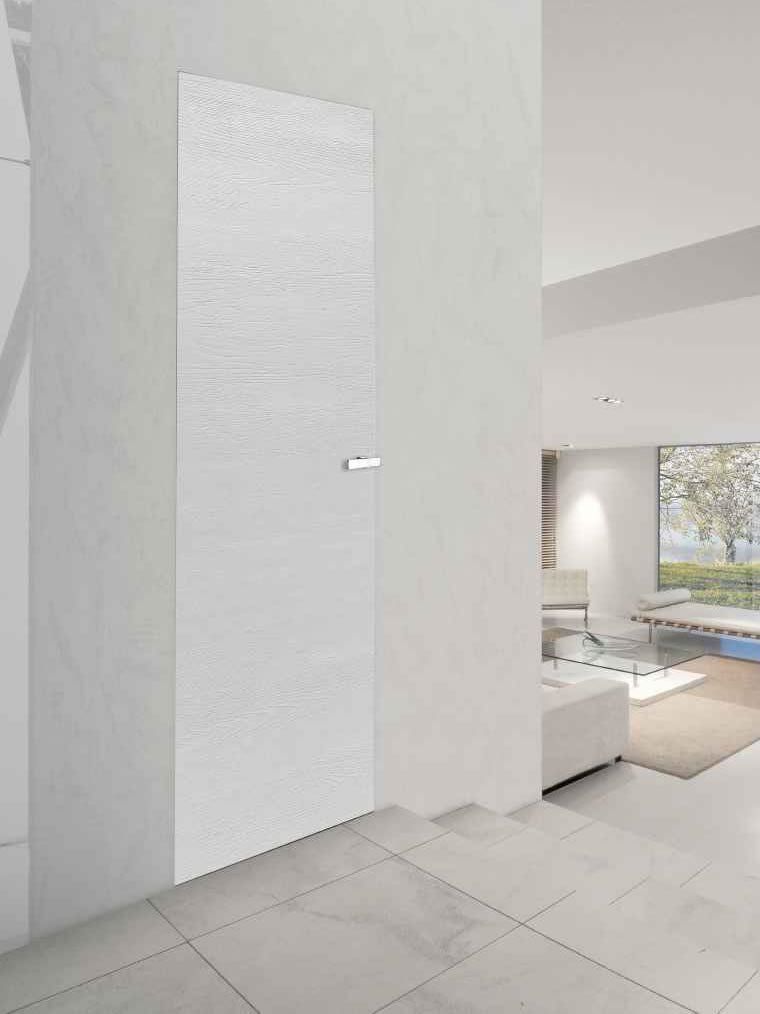 Porta bianca testurizzata a filo con una parete bianca in un ambiente interno moderno.