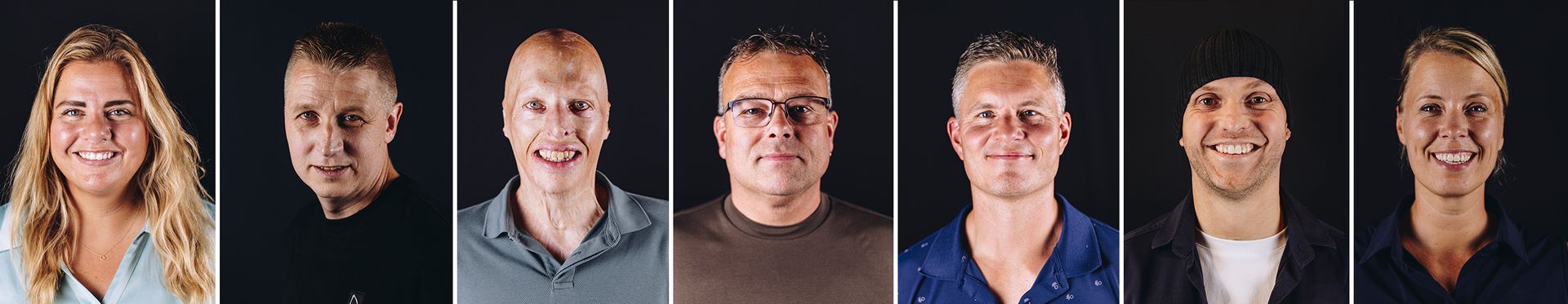 Zeven mensen glimlachen tegen een zwarte achtergrond.