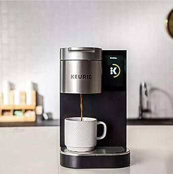 A keurig coffee maker is pouring coffee into a cup on a counter.